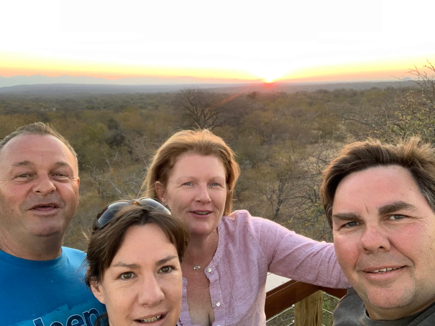 A treetop sundowner deck overlooks the bush at sunset.